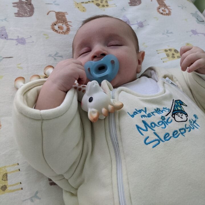 Baby boy sleeping in crib on back wearing Baby Merlin's Magic Sleepsuit