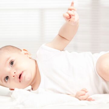 Baby rolling onto side showing signs of developmental readiness to transition from the swaddle.