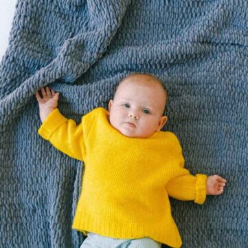 Baby lying on a moss stitch blanket.