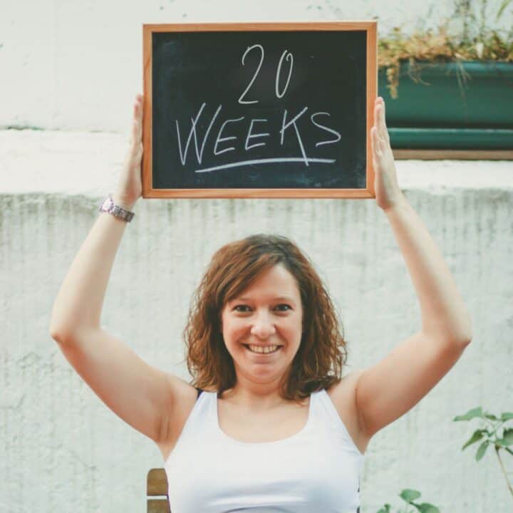 Pregnant woman holding a 20 weeks sign.