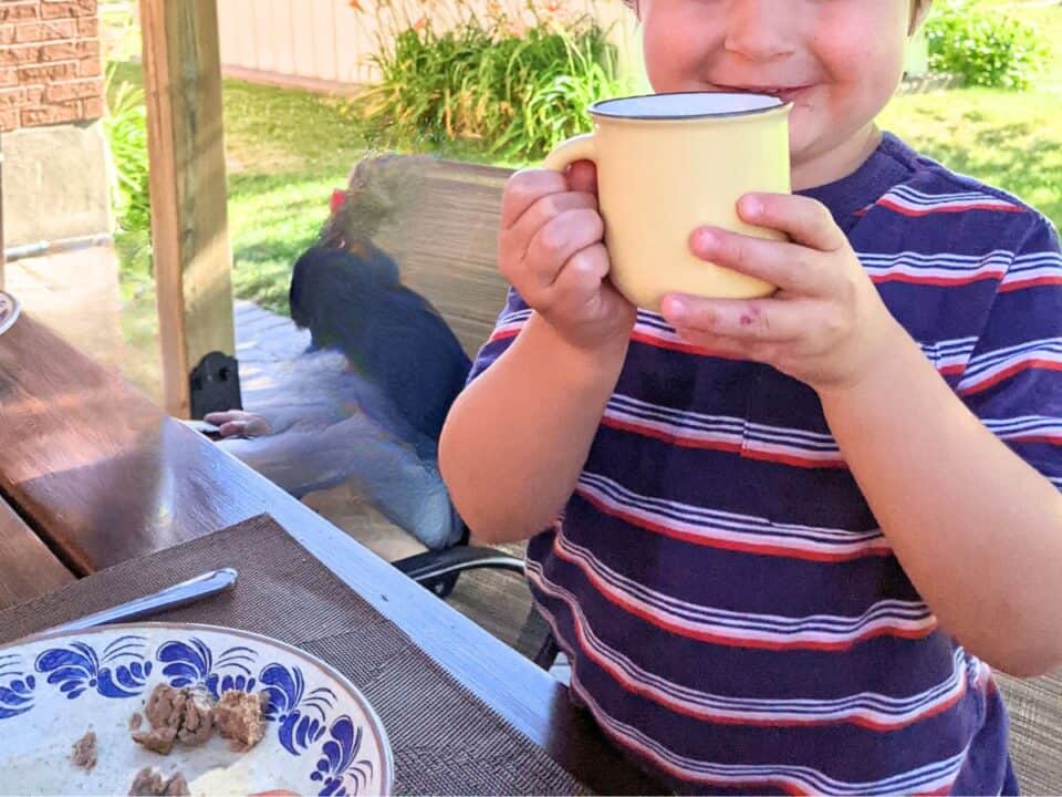boy drinking out of open glass cup