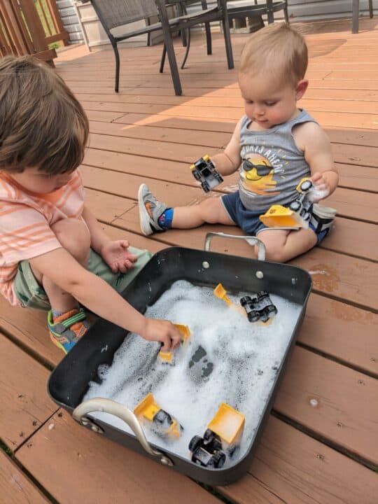 Two toddlers playing with trucks in bubles