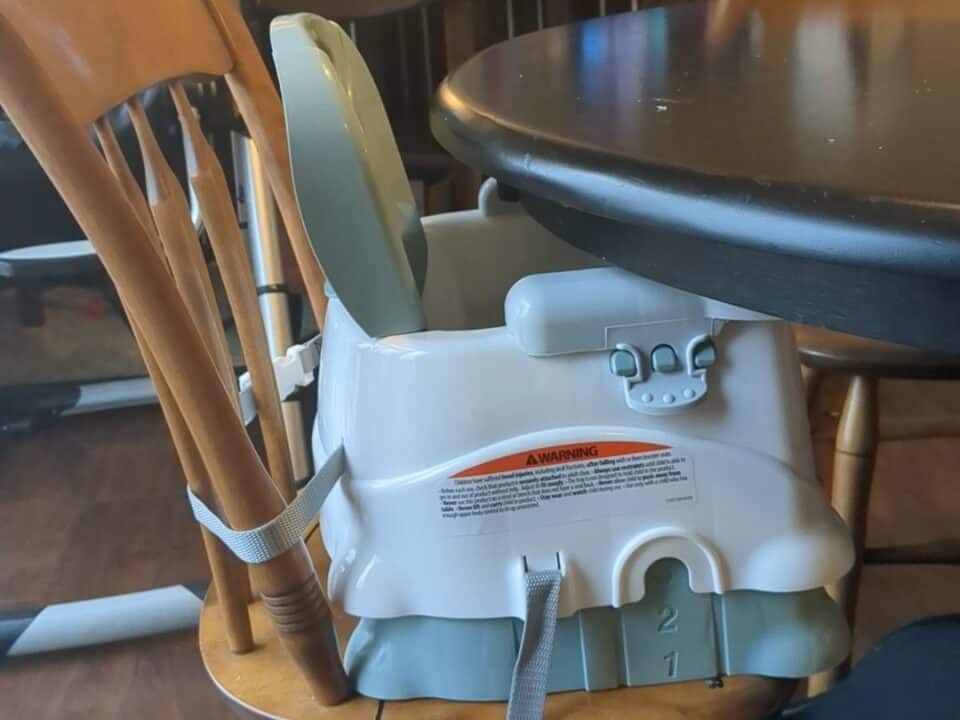 Fisher Price booster seat strapped to chair at table