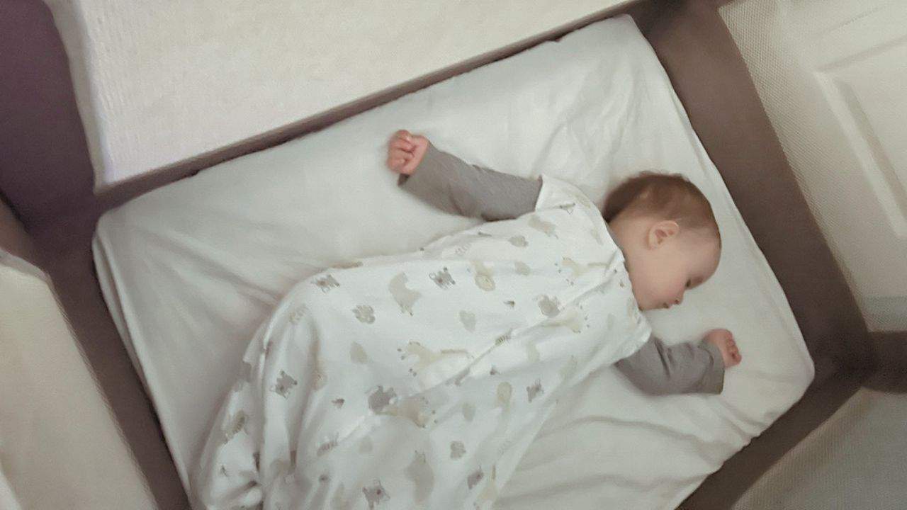 Baby sleeping in a sleep sack in a playard