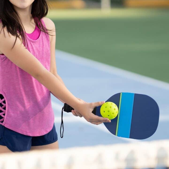 Woman playing pickleball with a colorful racket