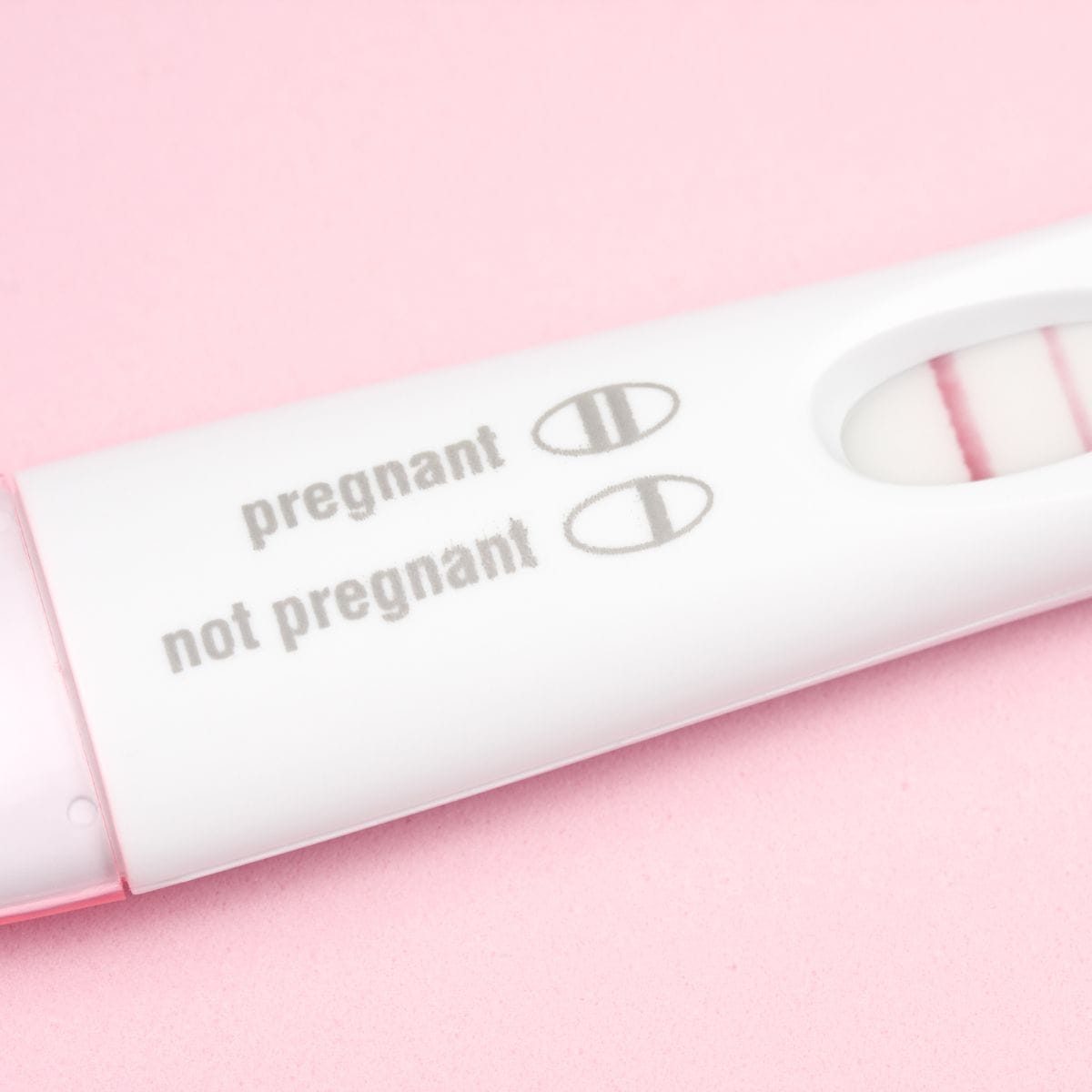 Positive First Response Early Results pregnancy test on a pink background.