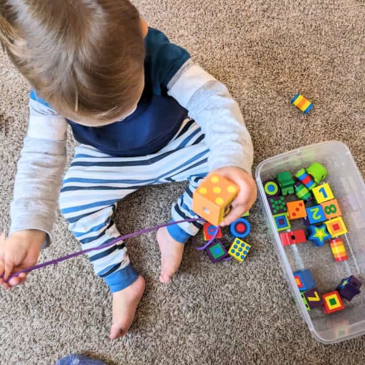 two year old playing with beading toy