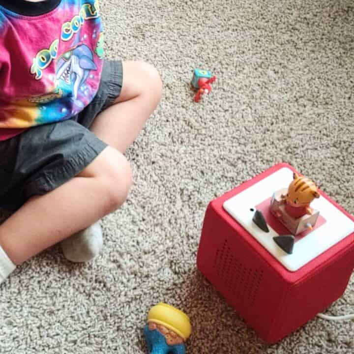 Toddler with Toniebox player and Daniel Tiger figurine